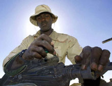 An American soldier stationed in Kuwait cleans his gun.