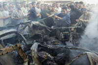 Palestinians try to rescue charred bodies from the remains of a car hit by an Israeli helicopter in Gaza, June 11, 2003