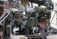 Israeli police inspect the charred remains of a bus destroyed by a suicide bomber in a attack Jerusalem attack, June 11, 2003